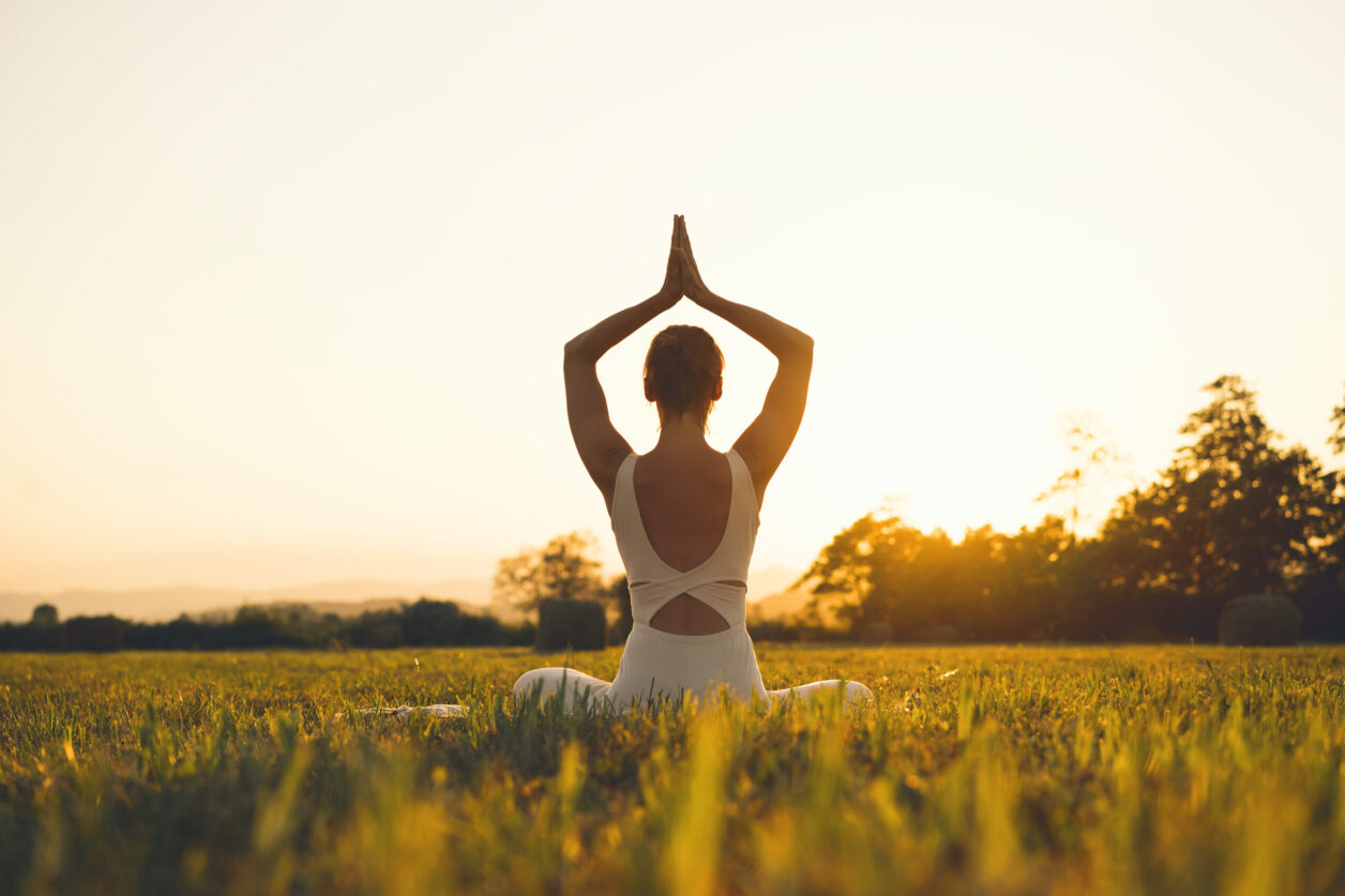 Young woman practicing yoga on nature. Girl meditating outdoors. Female with slim, strength and flexibility body. Healthy lifestyles. Concept of vitality, calmness, relax, mindfulness, zen energy.