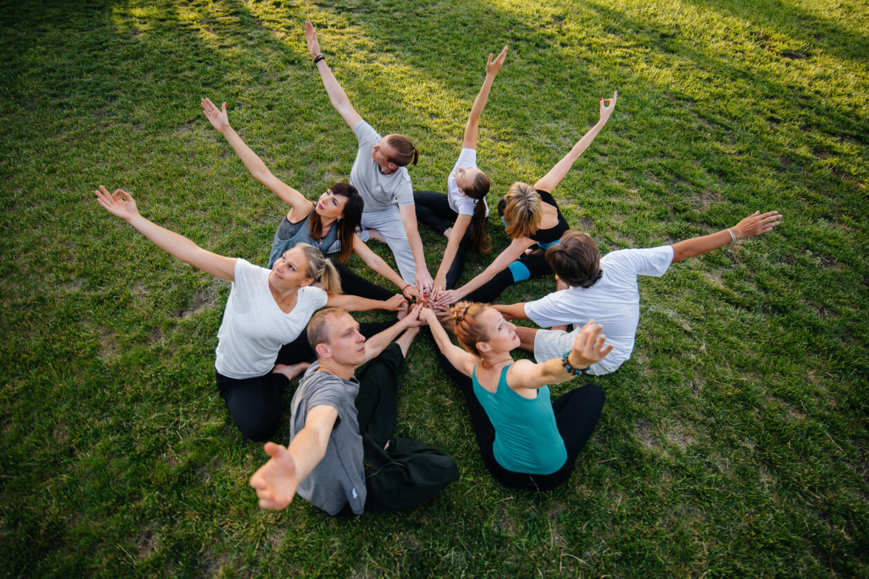 A group of people do yoga in a circle in the open air during sunset. Healthy lifestyle, meditation and Wellness