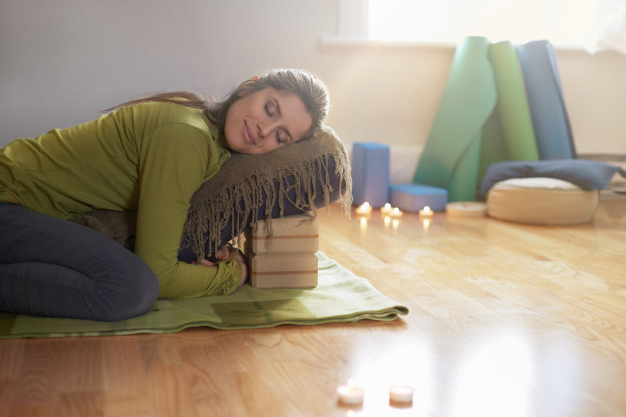 Serene lady relaxing and meditating on a yoga mat in a cosy house